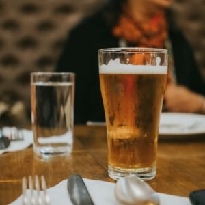 a woman sitting at a table with a glass of beer